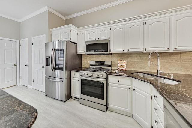 kitchen featuring appliances with stainless steel finishes, tasteful backsplash, dark stone counters, sink, and white cabinets