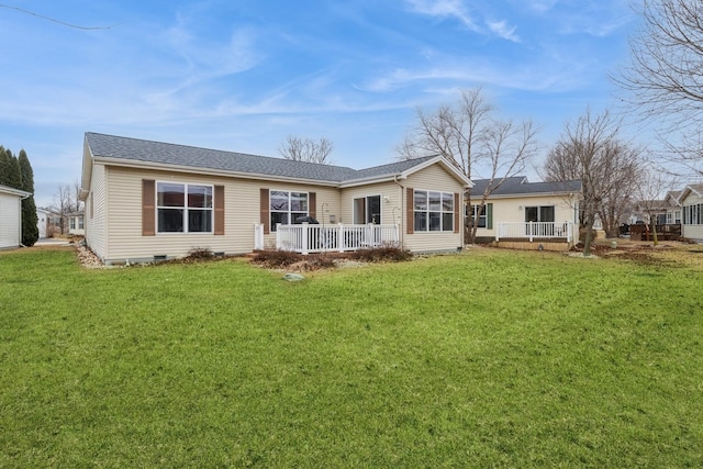 rear view of property featuring a wooden deck and a lawn