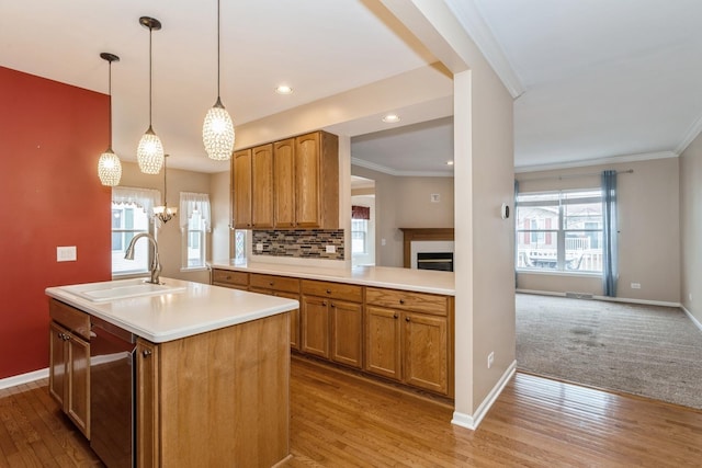 kitchen with pendant lighting, an island with sink, sink, decorative backsplash, and ornamental molding