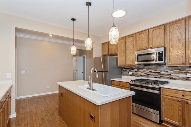 kitchen with sink, appliances with stainless steel finishes, a kitchen island with sink, backsplash, and decorative light fixtures