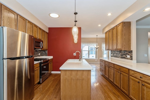 kitchen featuring sink, hardwood / wood-style flooring, hanging light fixtures, stainless steel appliances, and a center island with sink