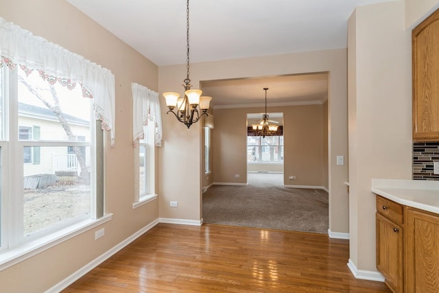 unfurnished dining area featuring crown molding, light hardwood / wood-style floors, and a chandelier