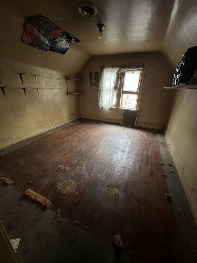 additional living space with hardwood / wood-style flooring and vaulted ceiling