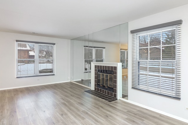 unfurnished living room with hardwood / wood-style floors and a tiled fireplace