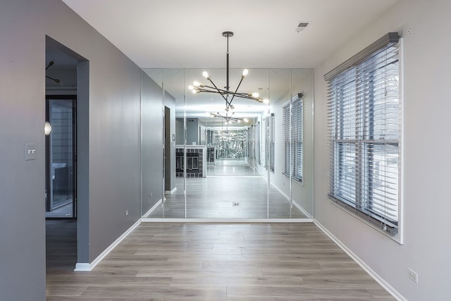 hallway featuring hardwood / wood-style flooring and an inviting chandelier