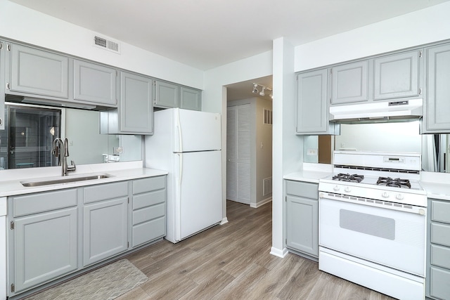 kitchen with gray cabinetry, sink, white appliances, and light hardwood / wood-style flooring