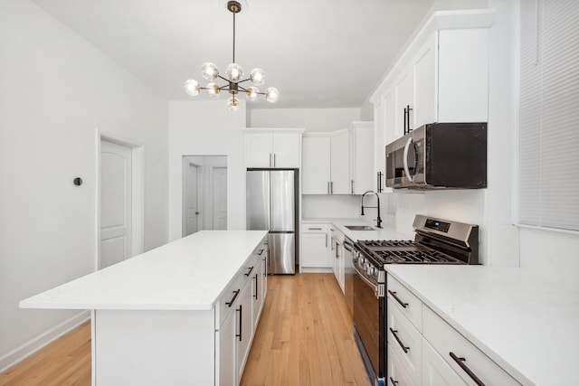 kitchen with a kitchen island, appliances with stainless steel finishes, white cabinetry, sink, and light wood-type flooring