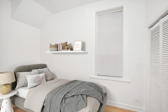 bedroom with vaulted ceiling, a closet, and light wood-type flooring