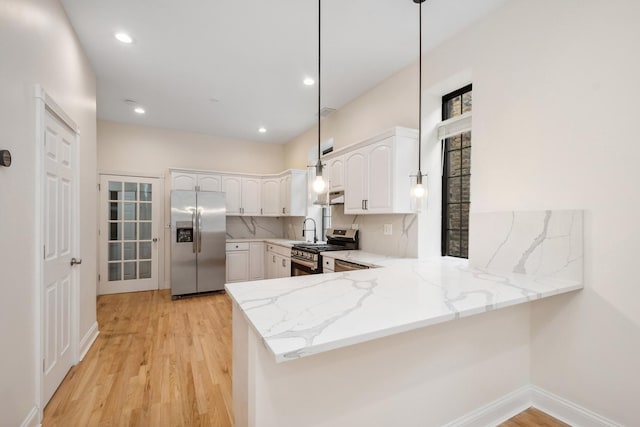 kitchen featuring white cabinetry, decorative light fixtures, kitchen peninsula, stainless steel appliances, and backsplash