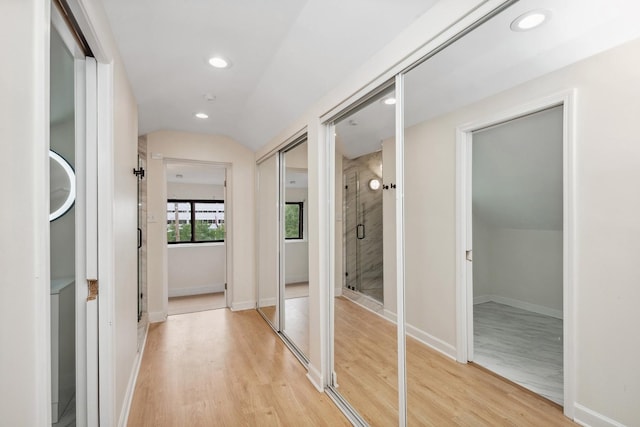 hall with vaulted ceiling and light hardwood / wood-style flooring