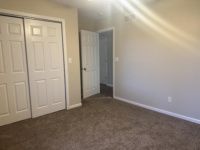 unfurnished bedroom with dark carpet and a closet