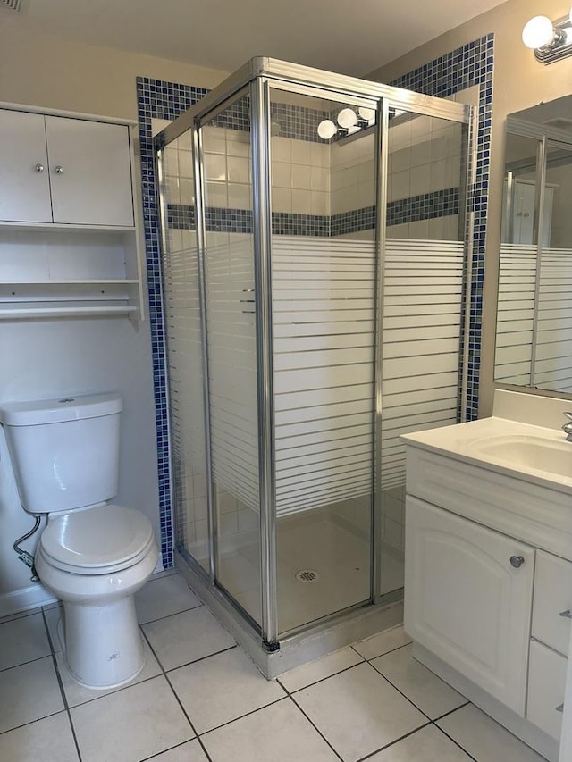 bathroom featuring toilet, vanity, tile patterned floors, and walk in shower