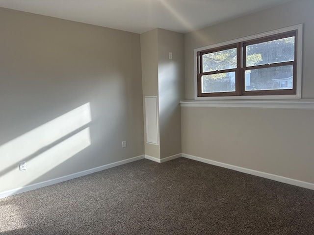 spare room featuring dark carpet