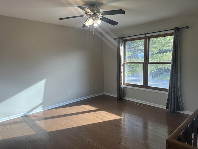 empty room featuring dark hardwood / wood-style flooring, ceiling fan, and a healthy amount of sunlight