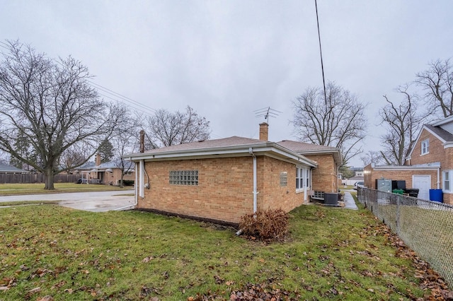 view of side of home with central AC and a yard