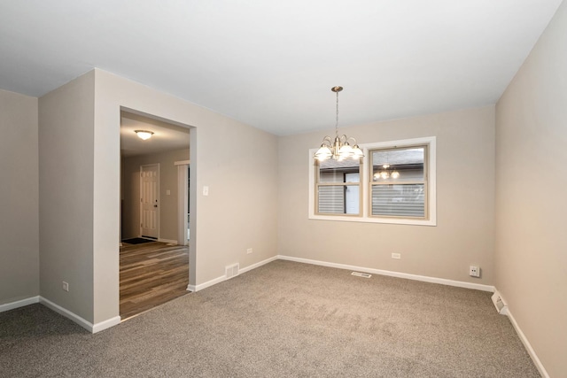 carpeted empty room featuring a notable chandelier