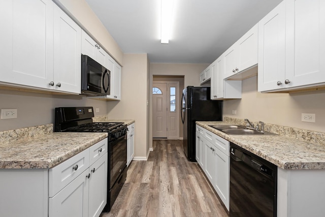 kitchen featuring white cabinetry, sink, black appliances, and light wood-type flooring