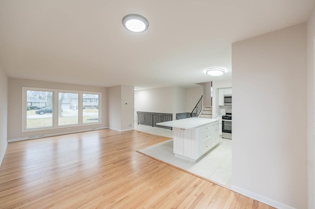 kitchen with light wood-type flooring, a breakfast bar, stainless steel appliances, white cabinets, and a center island