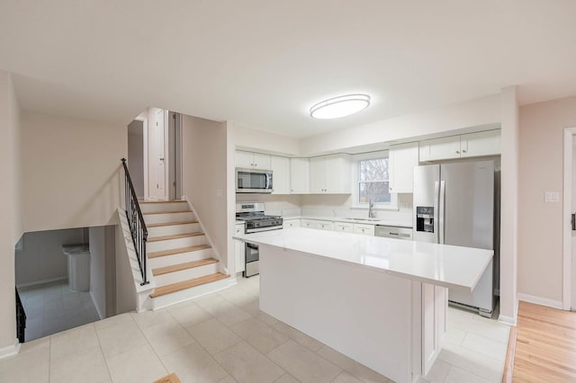 kitchen featuring a center island, sink, stainless steel appliances, light tile patterned floors, and white cabinets