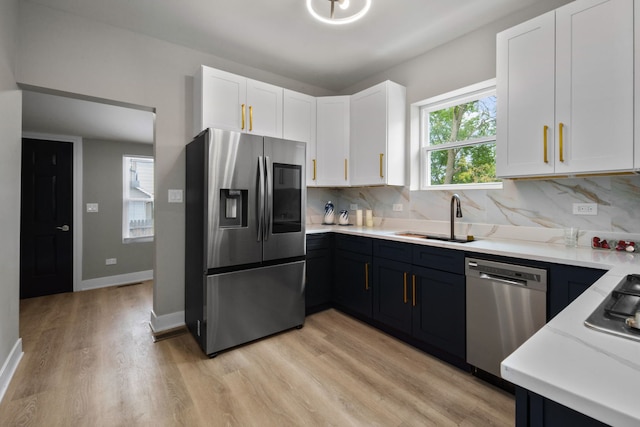 kitchen with white cabinetry, sink, appliances with stainless steel finishes, and light hardwood / wood-style flooring