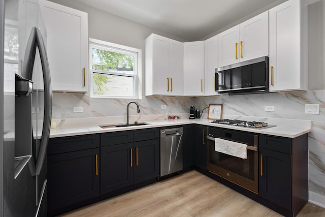 kitchen featuring backsplash, stainless steel appliances, sink, light hardwood / wood-style flooring, and white cabinetry