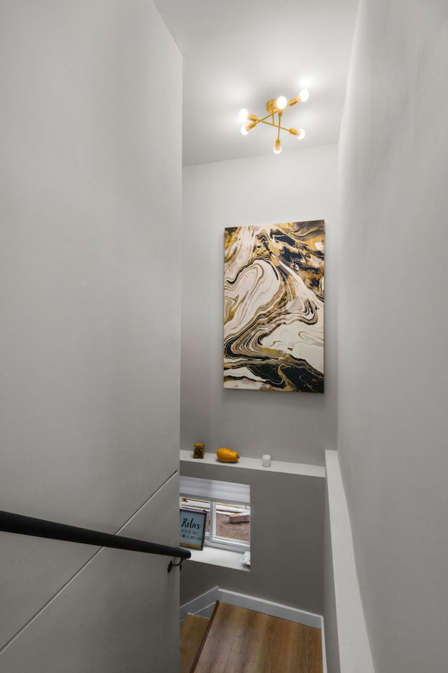 staircase with wood-type flooring and an inviting chandelier