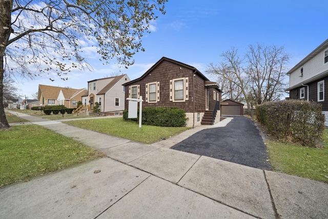 view of front of home featuring a front yard, a garage, and an outdoor structure