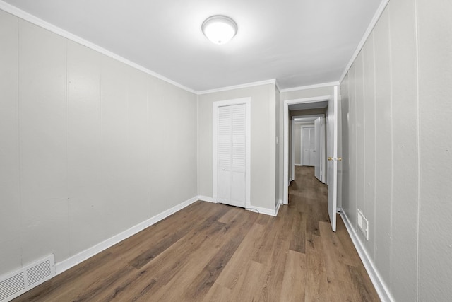 unfurnished bedroom featuring wood-type flooring and crown molding