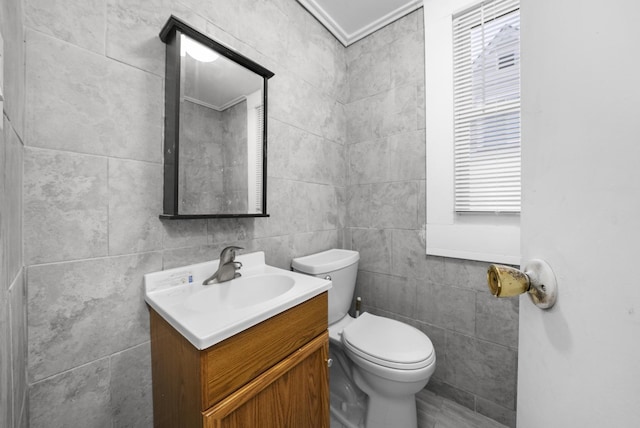 bathroom featuring vanity, toilet, ornamental molding, and tile walls