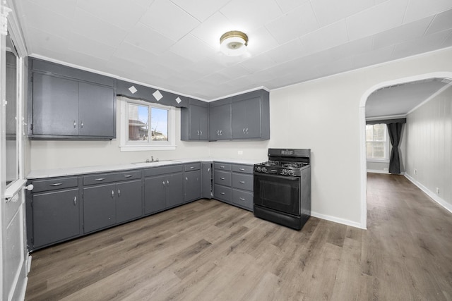 kitchen featuring black gas range, gray cabinets, light hardwood / wood-style floors, and sink