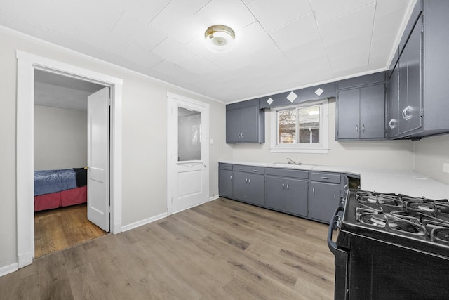 kitchen featuring black gas stove, light hardwood / wood-style floors, gray cabinets, and sink