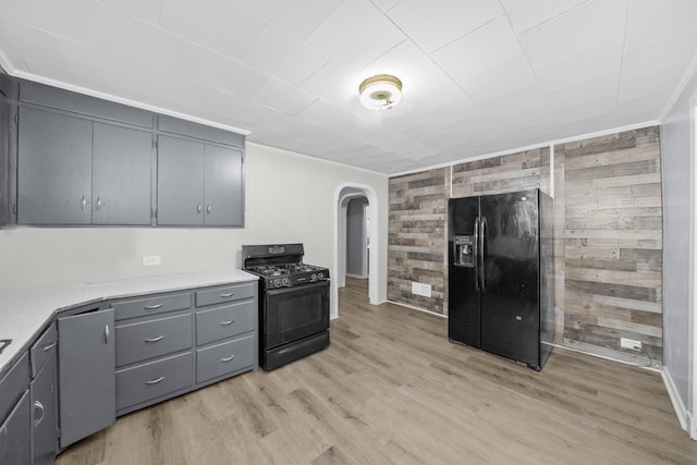 kitchen featuring gray cabinets, wooden walls, light hardwood / wood-style flooring, and black appliances