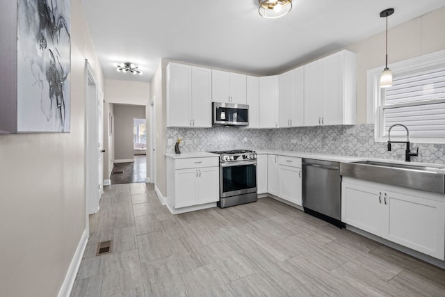 kitchen with white cabinetry, sink, decorative light fixtures, and appliances with stainless steel finishes