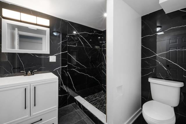 bathroom featuring vanity, toilet, tile walls, and a tile shower