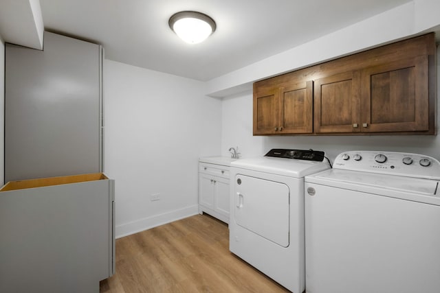 laundry room with cabinets, independent washer and dryer, and light hardwood / wood-style flooring