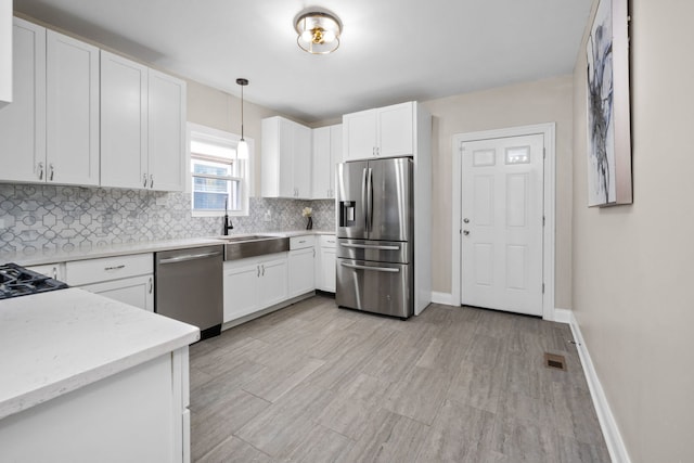 kitchen with sink, stainless steel appliances, decorative light fixtures, decorative backsplash, and white cabinets