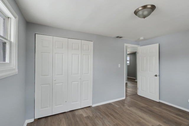 unfurnished bedroom featuring dark hardwood / wood-style flooring and a closet