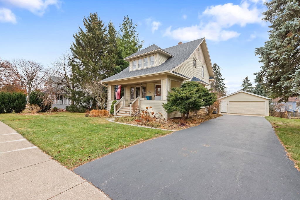 view of front of home with an outbuilding, a porch, a garage, and a front yard