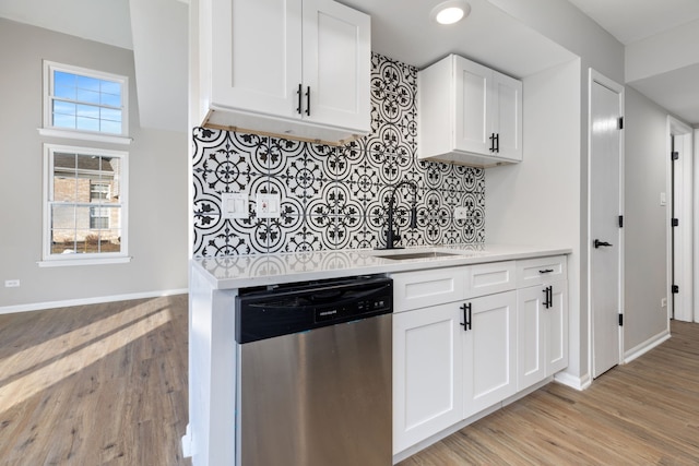 kitchen featuring light hardwood / wood-style floors, decorative backsplash, stainless steel dishwasher, white cabinets, and sink