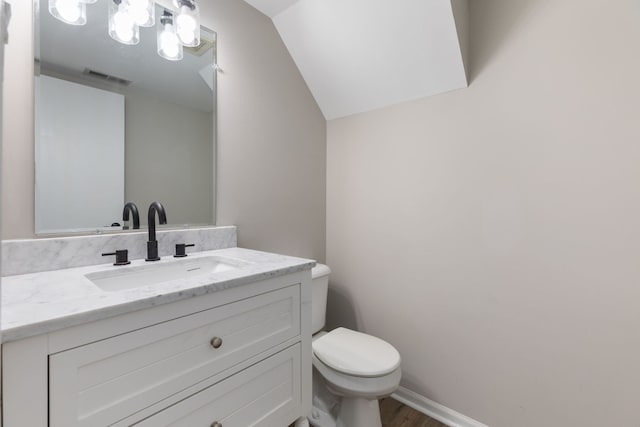 bathroom with vanity, toilet, hardwood / wood-style floors, and lofted ceiling