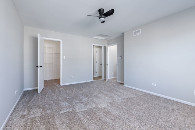 unfurnished bedroom featuring a walk in closet, ceiling fan, carpet, and a closet