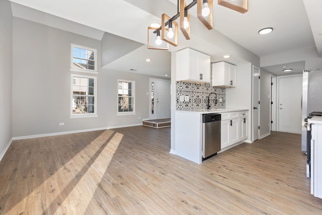 kitchen featuring light wood-type flooring, white cabinetry, decorative backsplash, and stainless steel appliances