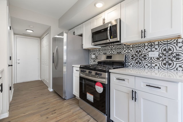 kitchen featuring white cabinetry, decorative backsplash, light hardwood / wood-style flooring, and stainless steel appliances