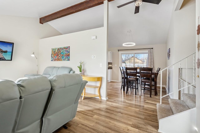 living room featuring ceiling fan, light hardwood / wood-style floors, and vaulted ceiling with beams