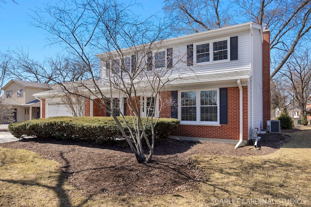 traditional-style home with central air condition unit, an attached garage, brick siding, and a chimney