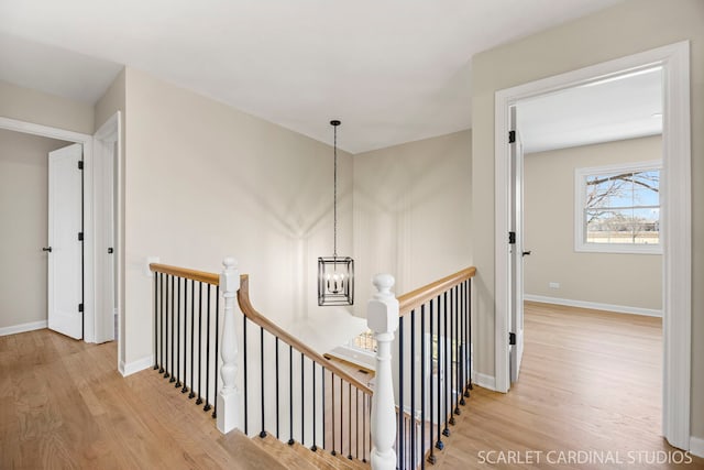 staircase featuring baseboards, a notable chandelier, and wood finished floors