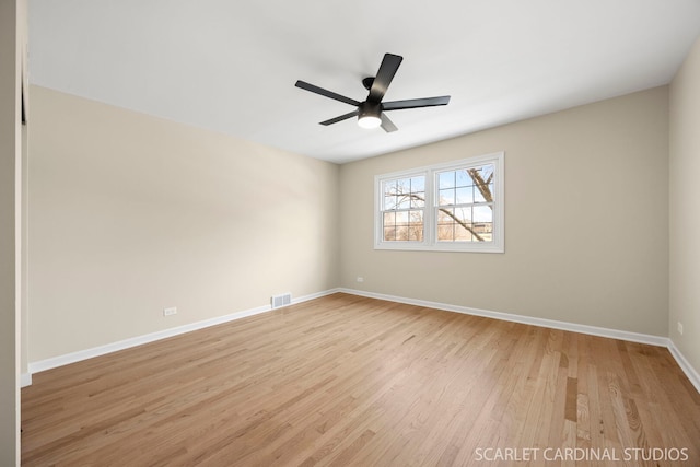 spare room with a ceiling fan, light wood-style floors, visible vents, and baseboards