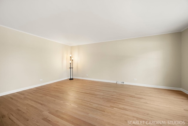 unfurnished room with visible vents, crown molding, light wood-type flooring, and baseboards