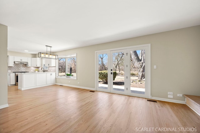 unfurnished living room featuring light wood finished floors, visible vents, and baseboards