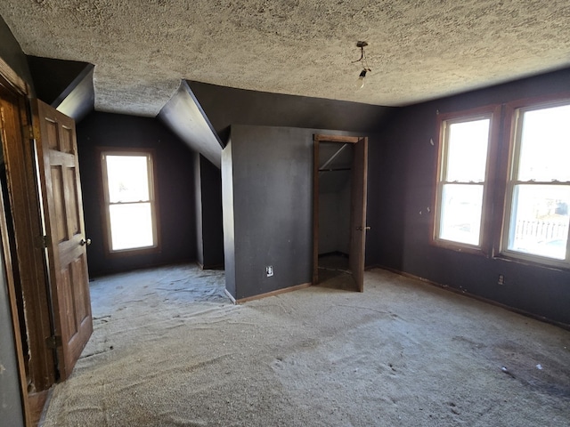 unfurnished bedroom featuring light colored carpet, lofted ceiling, and a textured ceiling